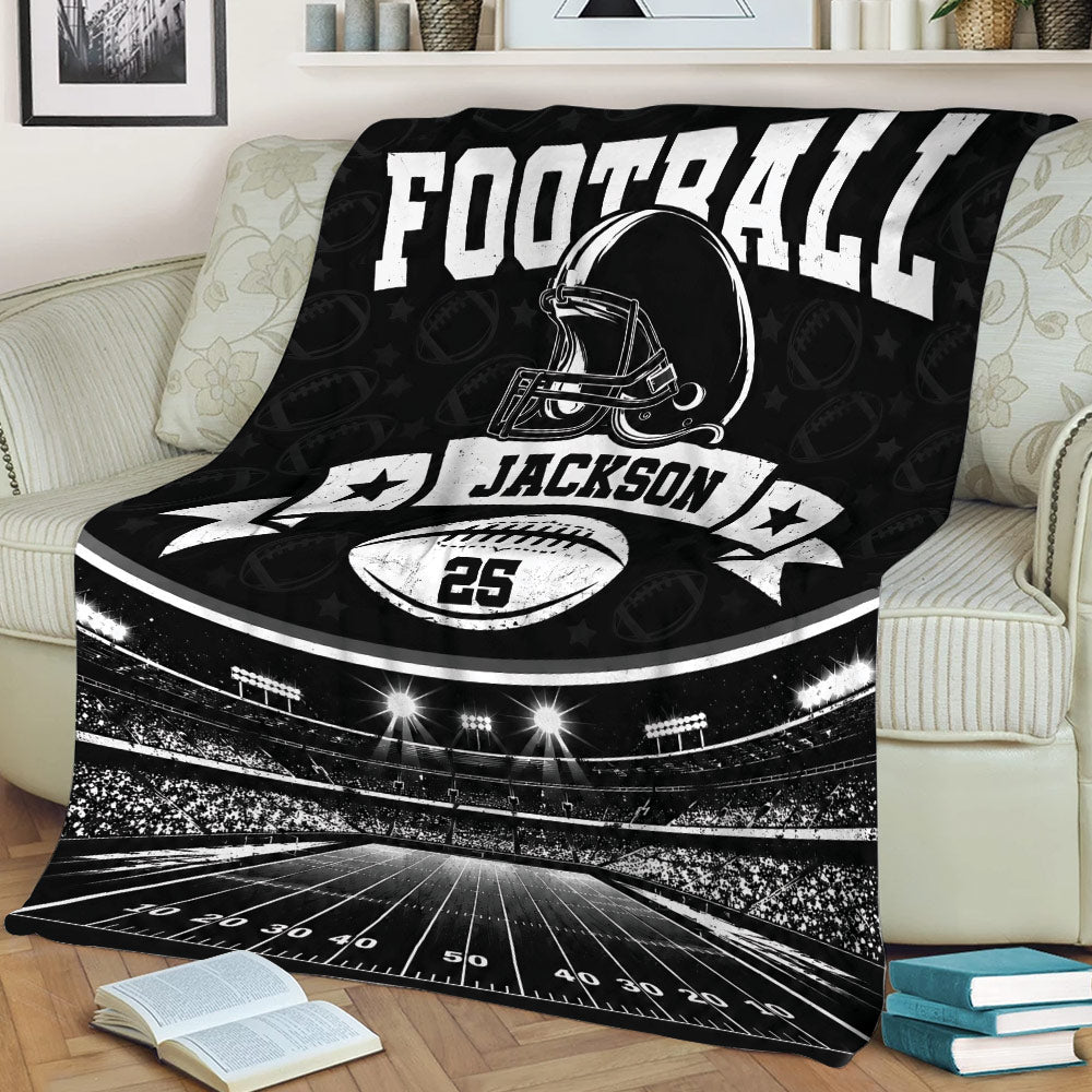 Black football blanket draped over a sofa with stadium field and helmet artwork