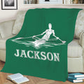 Green rowing throw blanket on a sofa featuring a white rower and boat on the water