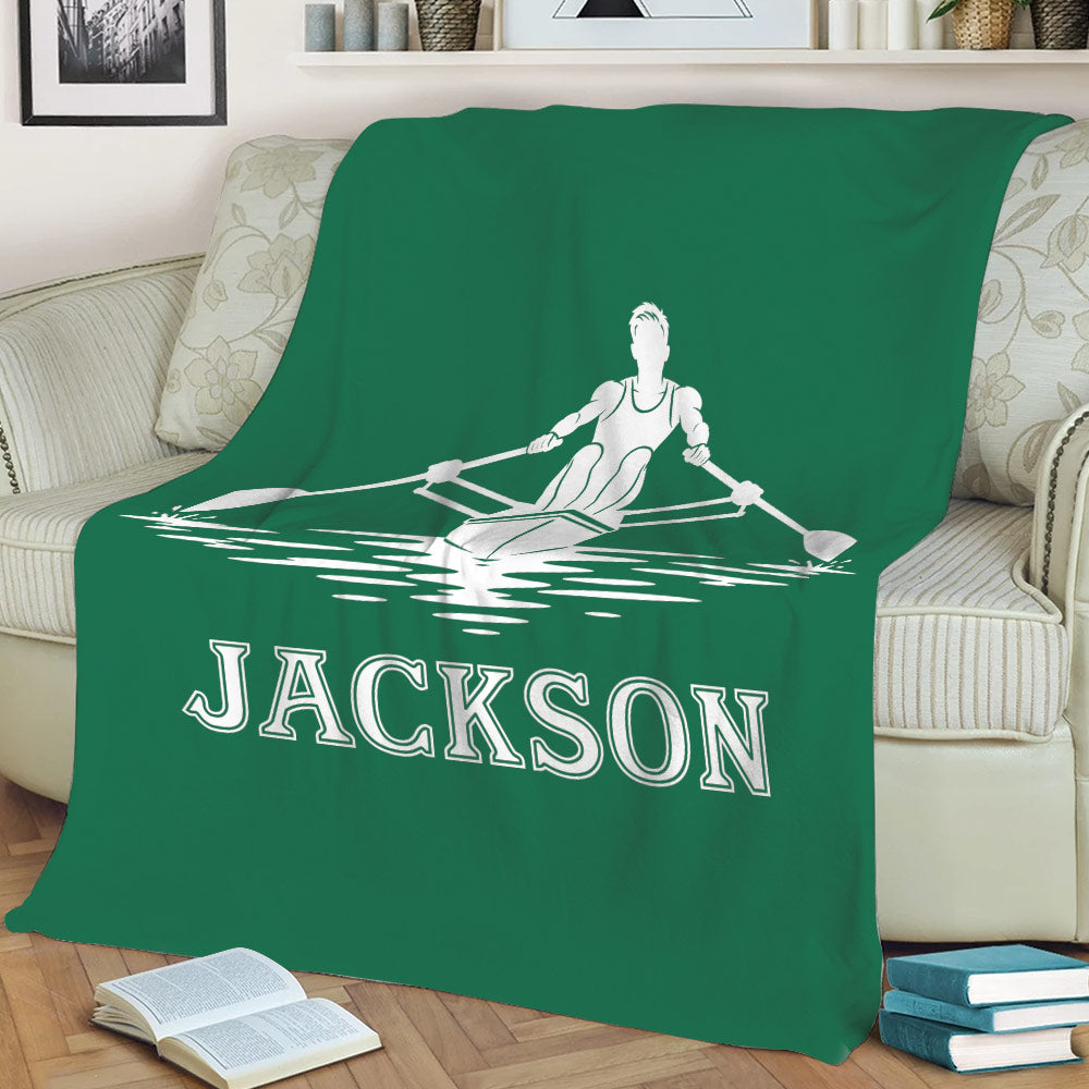 Green rowing throw blanket on a sofa featuring a white rower and boat on the water