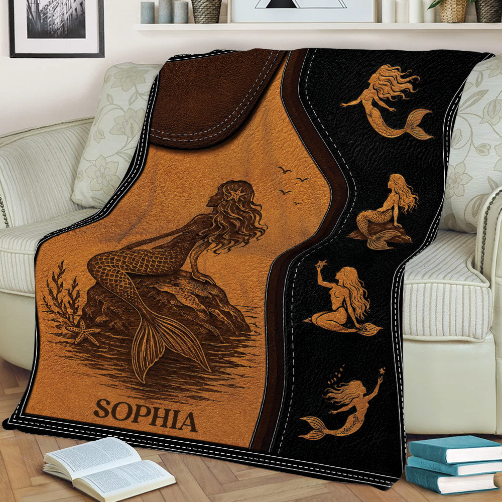 Custom mermaid throw blanket displayed on a couch with vintage ocean artwork and warm sepia tones