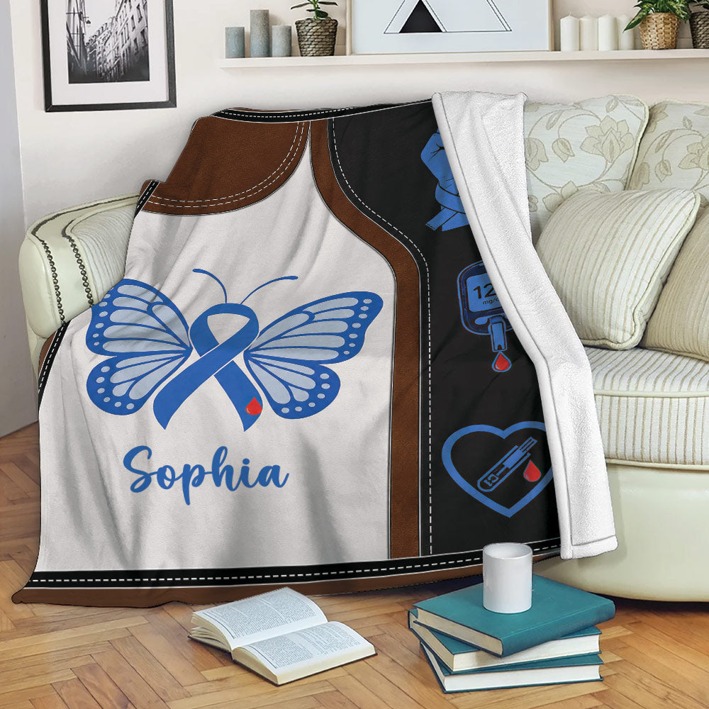 Diabetes awareness blanket displayed on a sofa with blue ribbon butterfly and glucose monitoring artwork