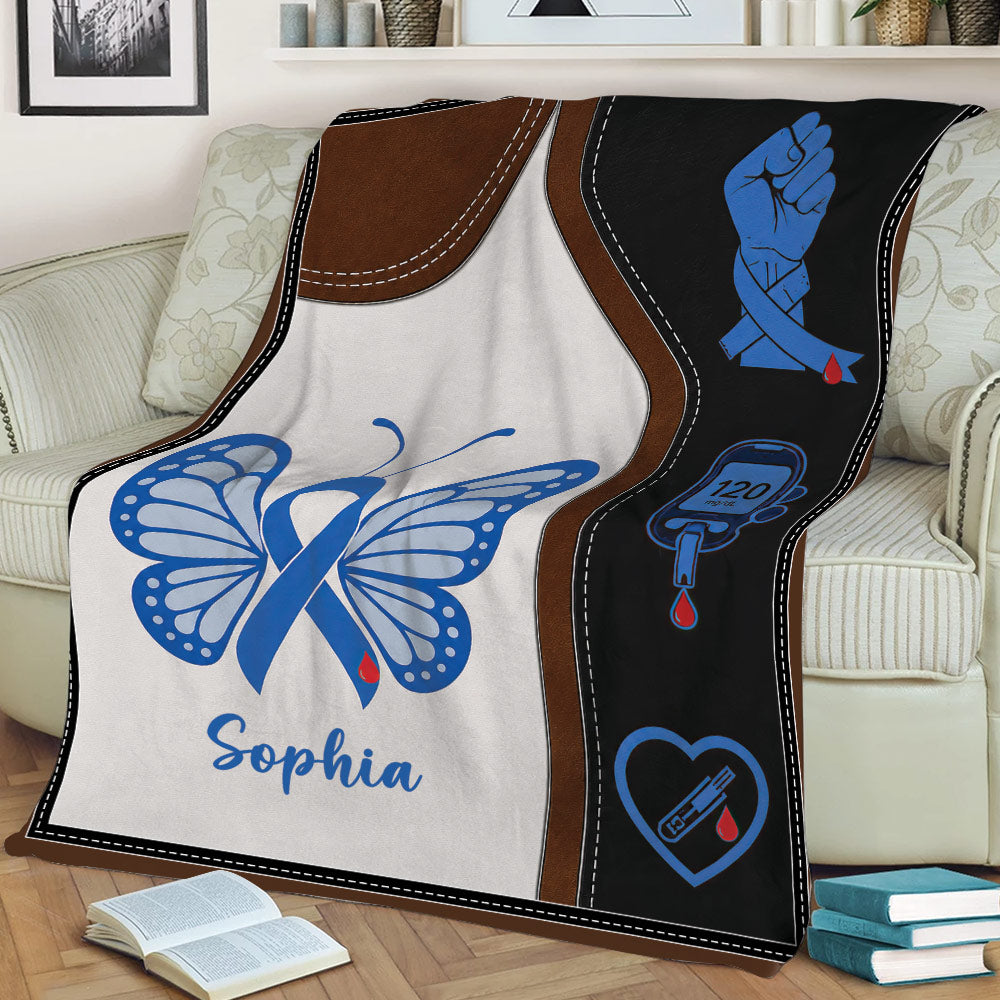 Diabetes throw blanket draped over a couch featuring blue awareness ribbon and blood glucose symbols