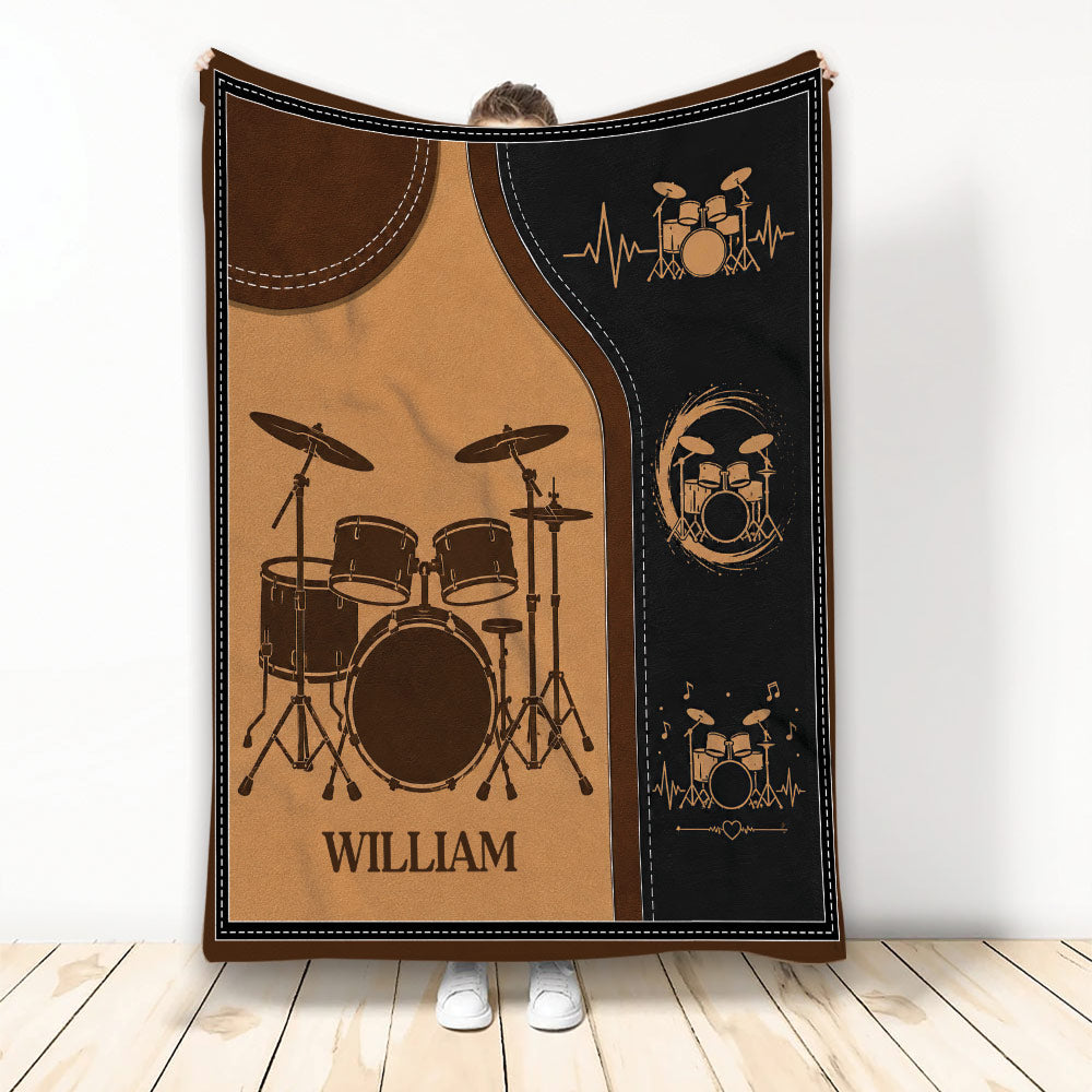 Drum throw blanket held up to show a vintage brown and black drum kit design