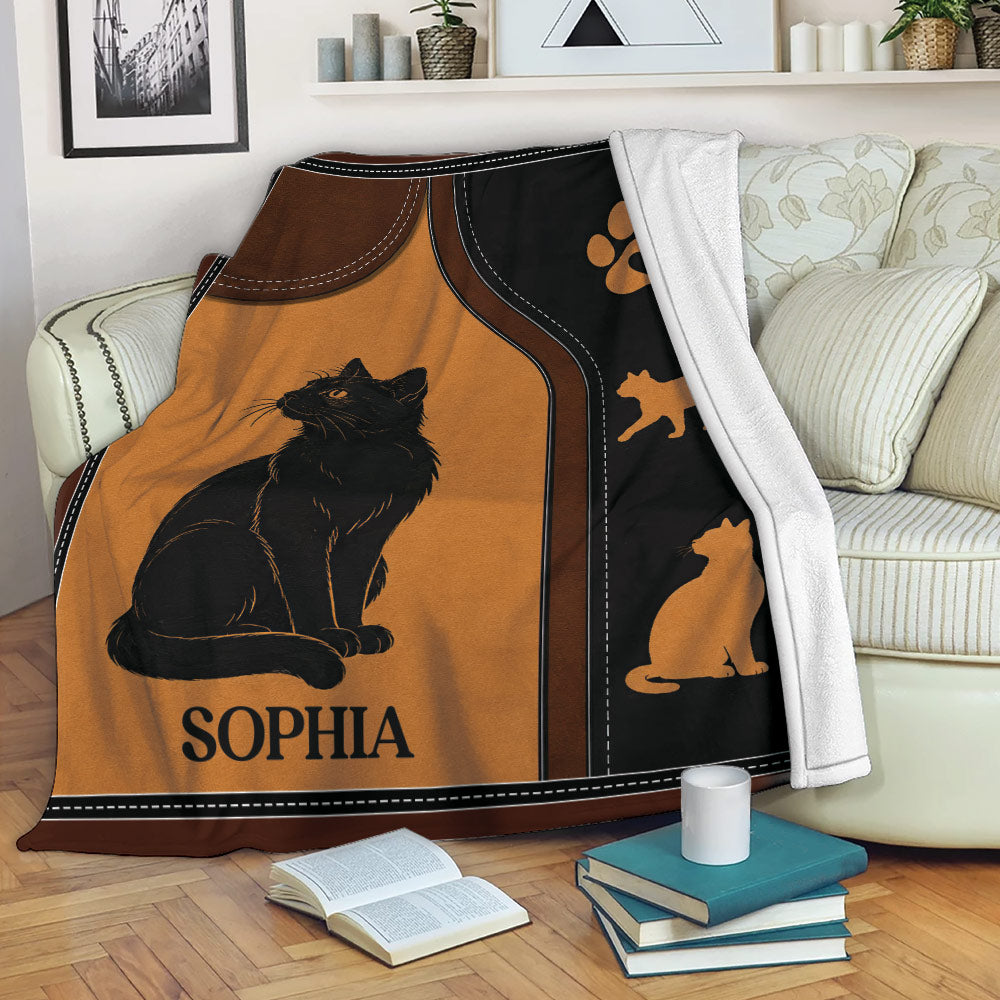 Black cat throw blanket draped over a sofa with warm orange artwork and cat-themed details