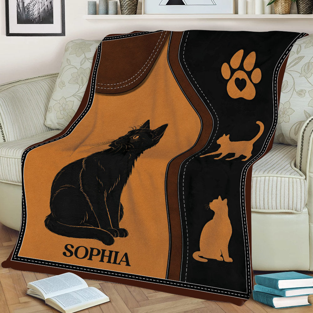 Black cat blanket displayed on a sofa with vintage-inspired orange, brown, and black artwork