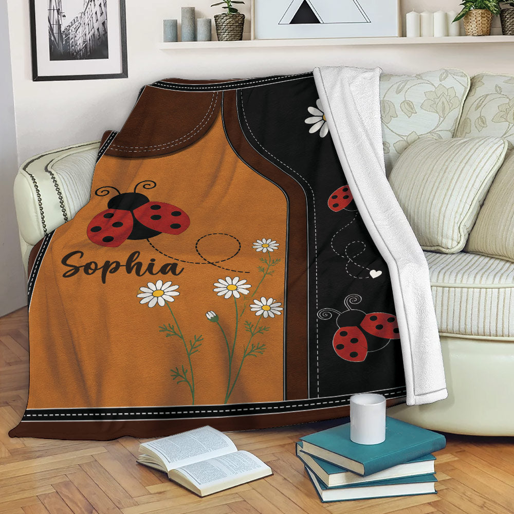 Ladybug blanket draped over a sofa with red ladybugs, white daisies, and warm brown floral artwork