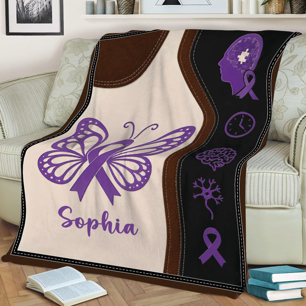 Purple Alzheimer's awareness blanket draped over a couch with butterfly, brain, and ribbon symbols