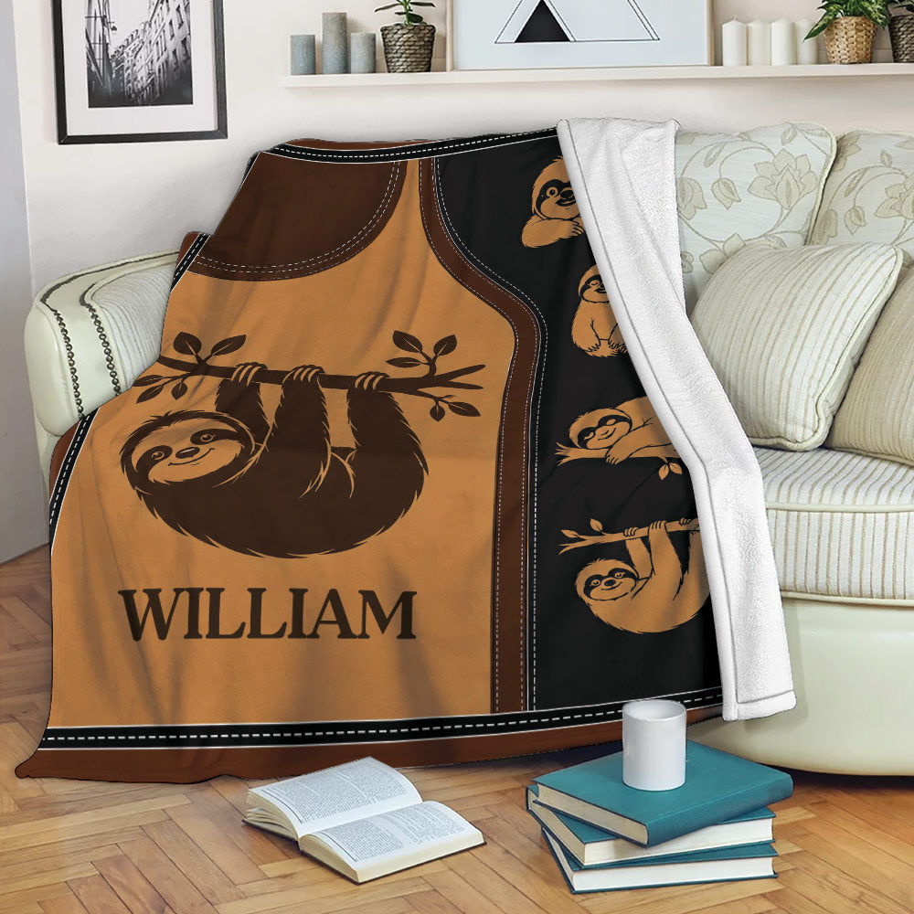 Sloth throw blanket draped over a sofa with warm brown artwork and repeating sloth illustrations