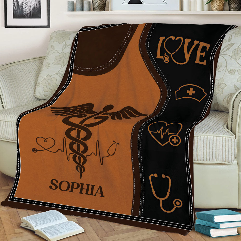 Nurse blanket draped over a couch featuring caduceus, stethoscope, and heart artwork