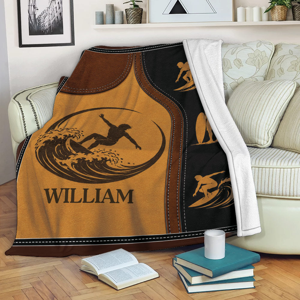 Surfing blanket draped over a sofa, featuring vintage wave-riding artwork in brown, gold, and black