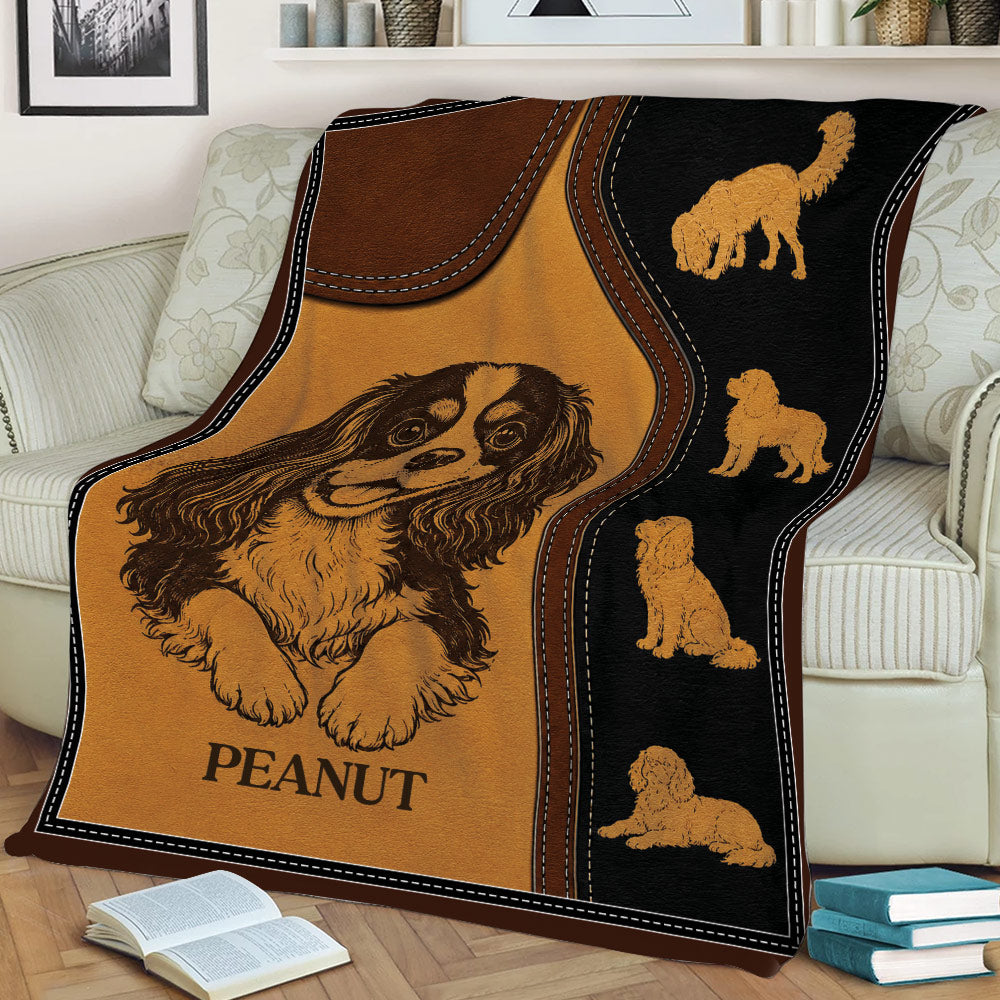 Cavalier King Charles blanket displayed on a couch with illustrated dog poses and rustic styling