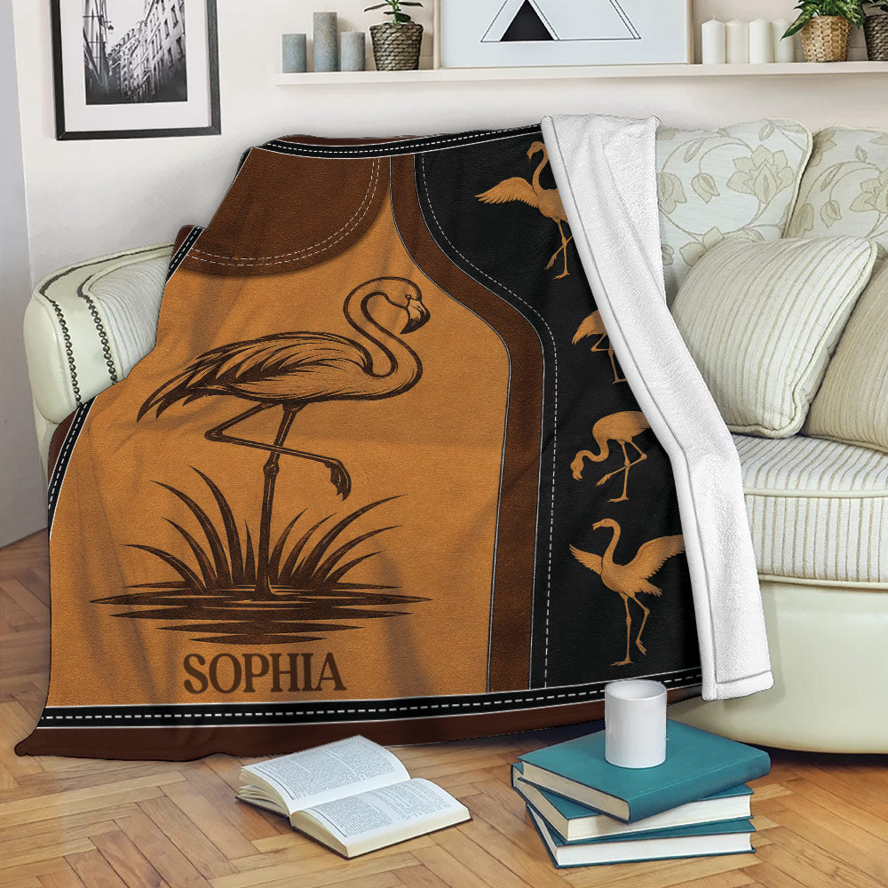 Flamingo throw blanket displayed on a sofa with golden bird artwork and a dark decorative border