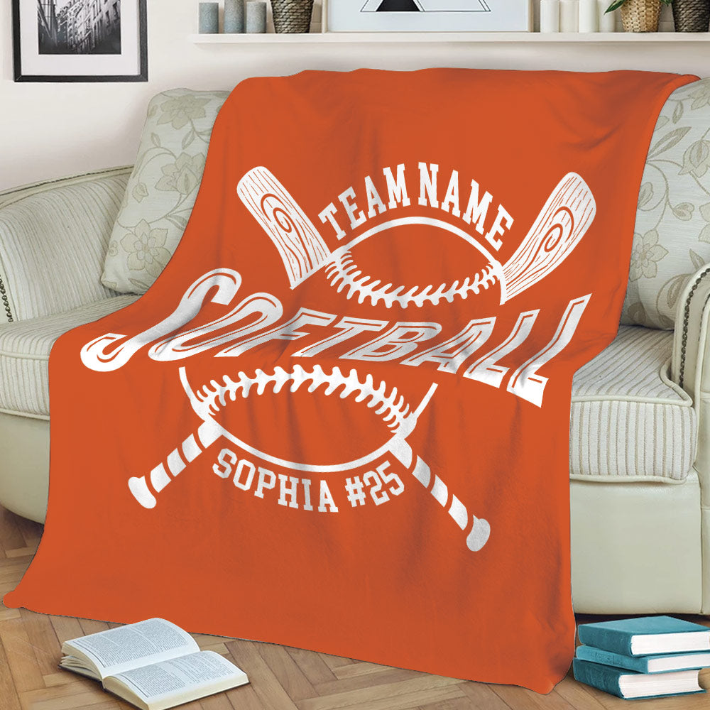 Orange softball blanket spread across a sofa with crossed bats and white softball artwork
