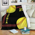 Softball blanket displayed on a sofa with bright yellow softballs and red stitching on a black background