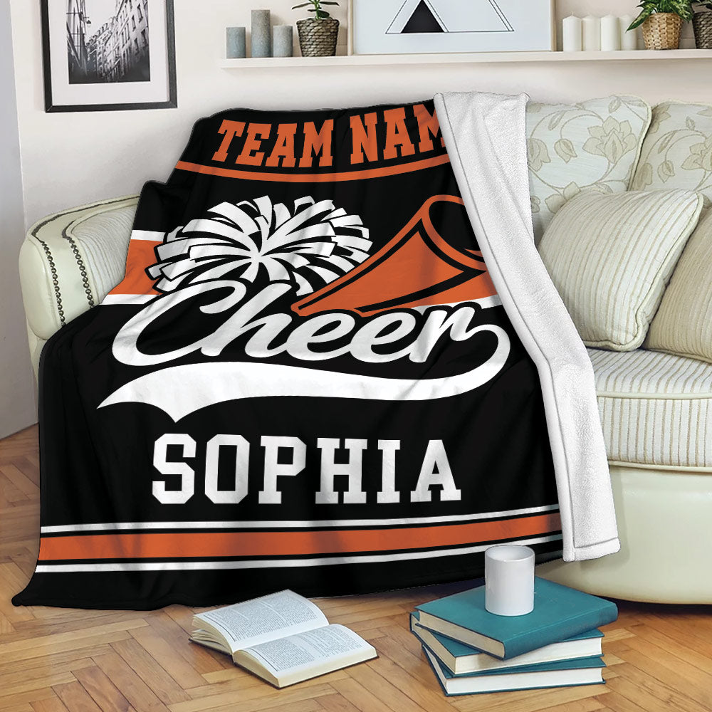 Cheerleading blanket draped over a sofa with pom-pom and megaphone artwork in black and orange