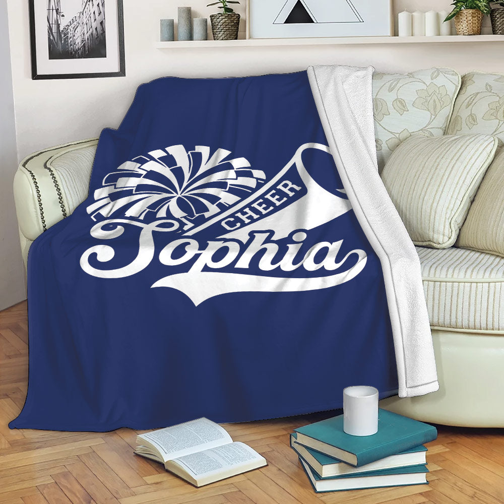 Navy cheerleading throw blanket draped over a sofa with pom-pom and megaphone design