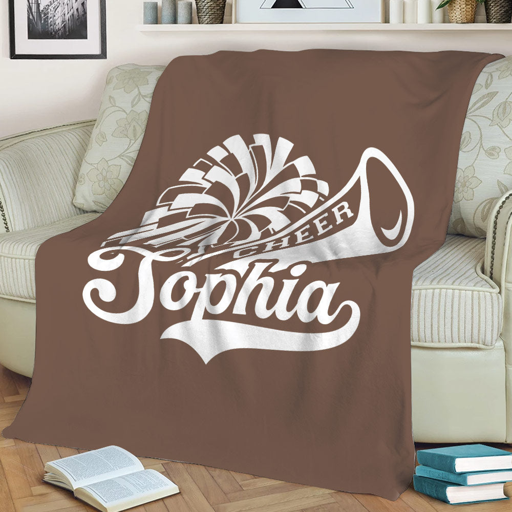 Brown cheerleading throw blanket displayed on a sofa with large white cheer graphic