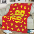 Red softball throw blanket draped over a sofa with yellow stitched hearts and bold athletic artwork