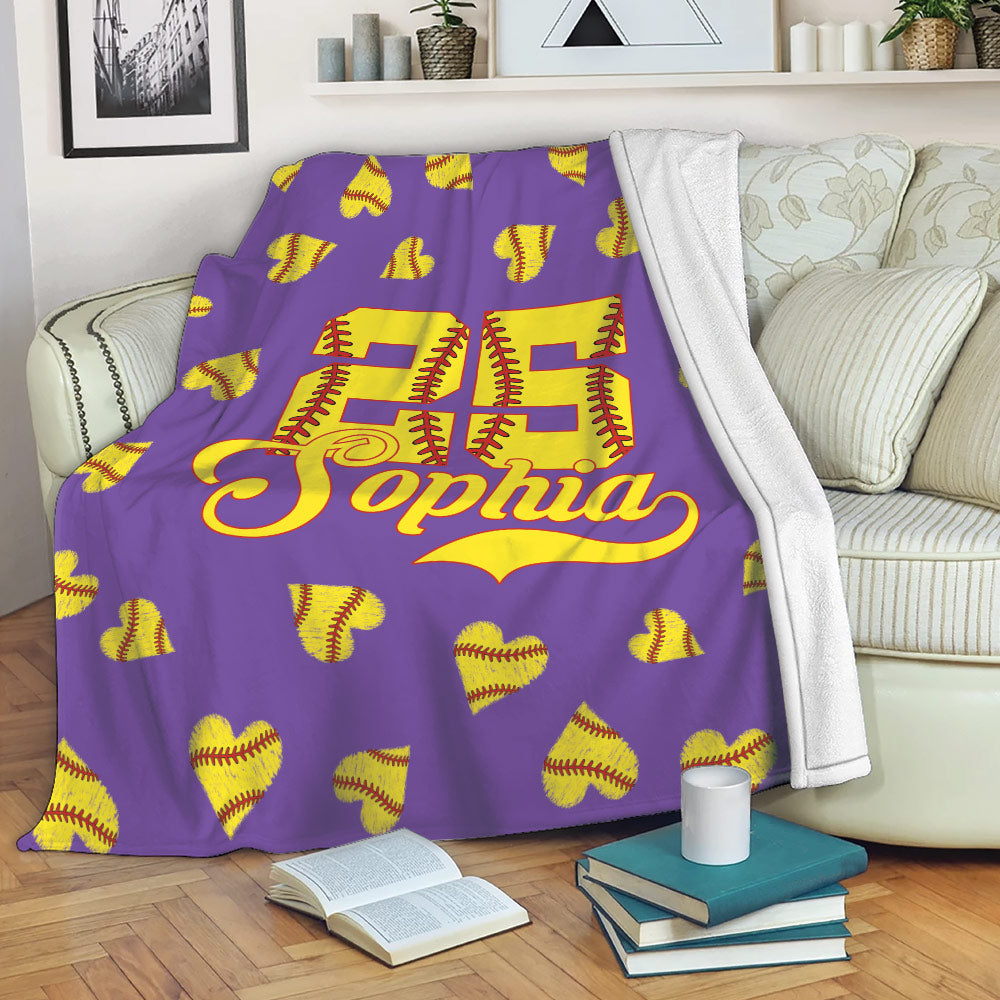Purple softball throw blanket draped over a sofa with yellow softball heart artwork