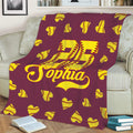 Maroon softball throw blanket on a couch with colorful yellow softball artwork