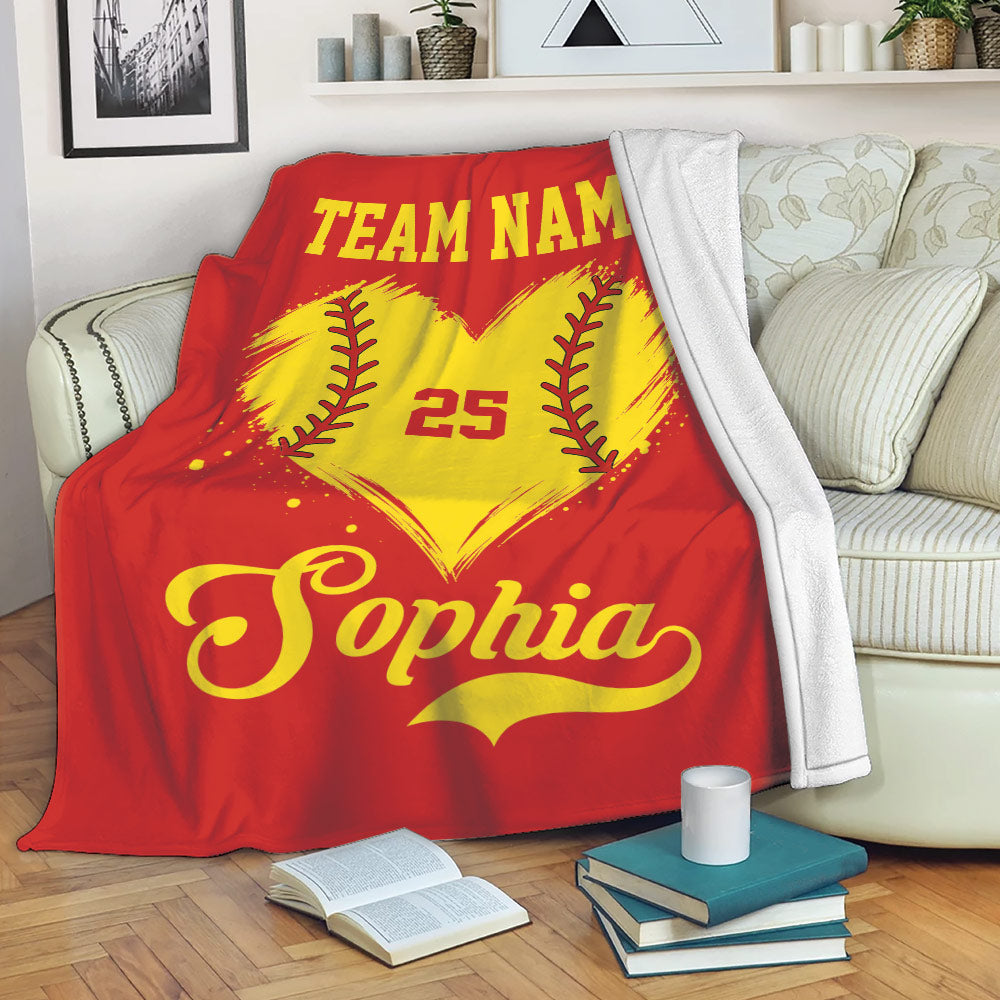 Red softball throw blanket displayed on a sofa with a yellow heart-shaped softball design