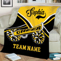 Yellow and black cheerleading throw blanket styled on a sofa with spirited pom-pom artwork