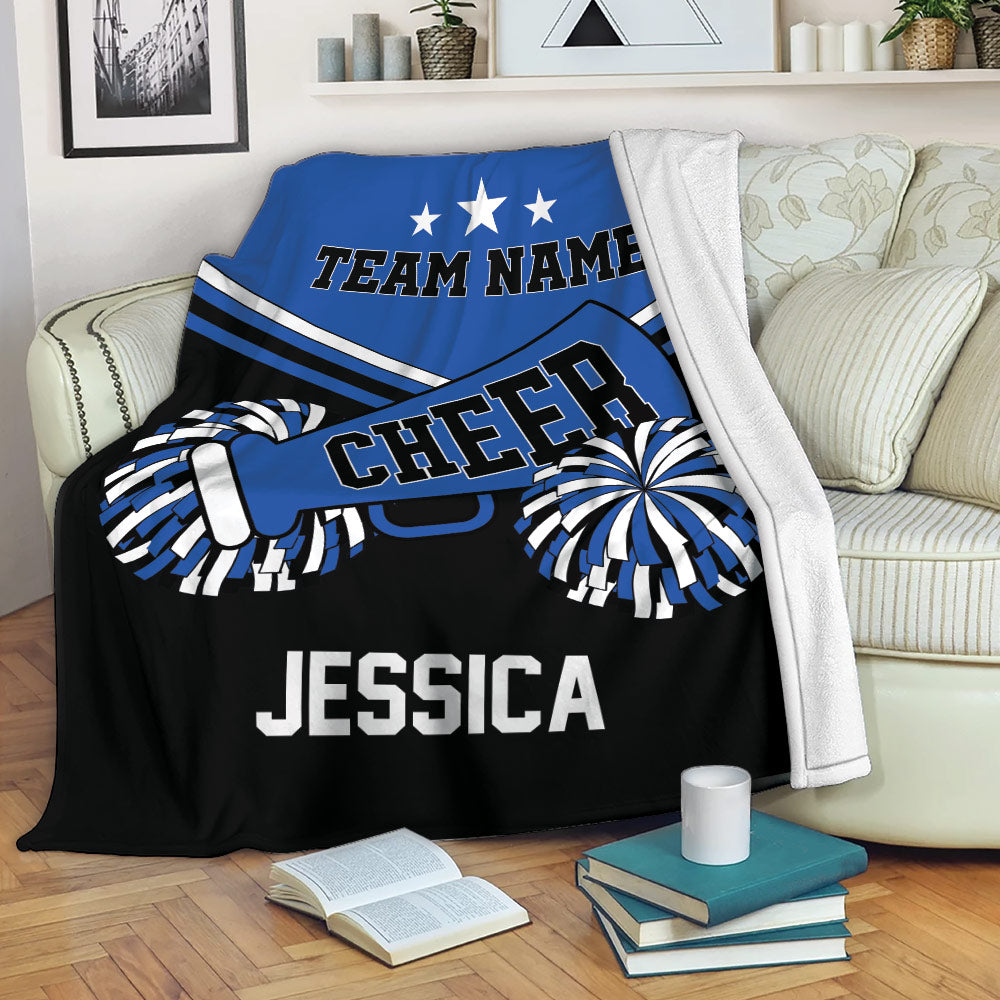Blue and black cheerleading throw blanket displayed on a sofa with pom-poms and megaphone artwork