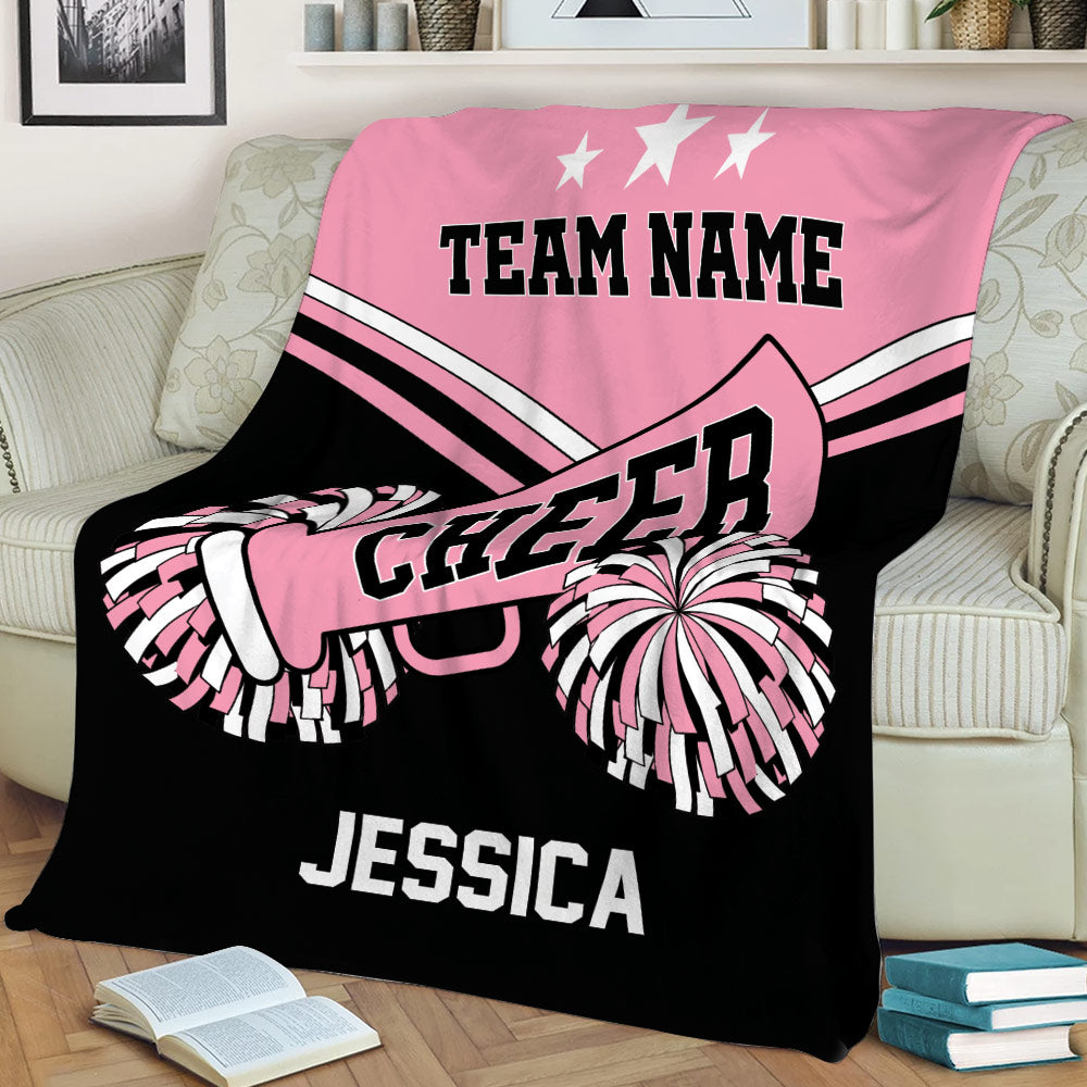 Pink and black cheerleading throw blanket draped over a sofa with pom-pom and megaphone artwork