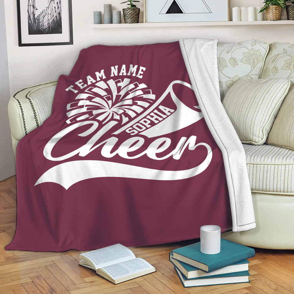 Maroon cheerleading blanket styled on a sofa with pom-pom and megaphone sports artwork