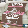 Brown and pink cheerleading throw blanket styled across a sofa with pom-pom and megaphone artwork