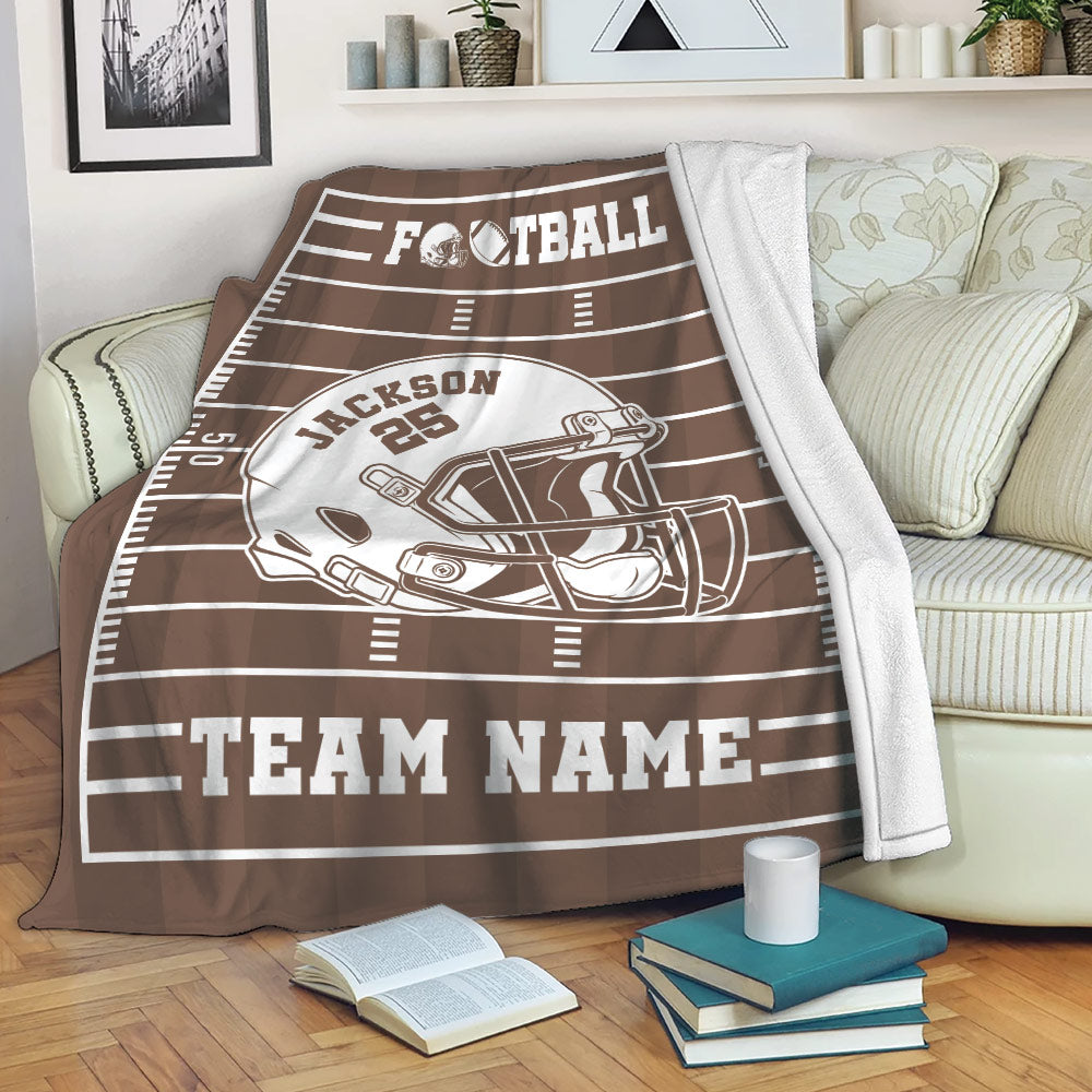 Brown football throw blanket draped over a sofa with field lines and bold helmet artwork