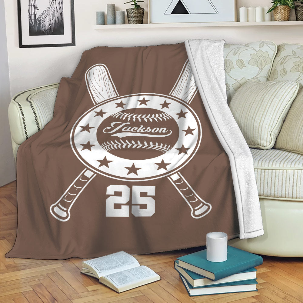 Brown baseball throw blanket displayed on a sofa with crossed bats and classic baseball emblem artwork