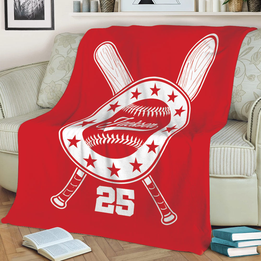 Red baseball throw blanket draped over a sofa with bold crossed bat and baseball emblem artwork