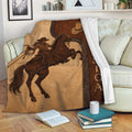 Cowgirl blanket draped over a sofa with horseback rider artwork and warm rustic Western tones