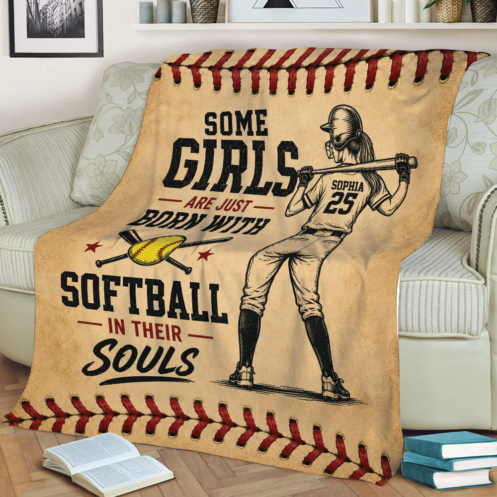 Girls softball throw blanket draped over a couch with female batter artwork and softball-themed border