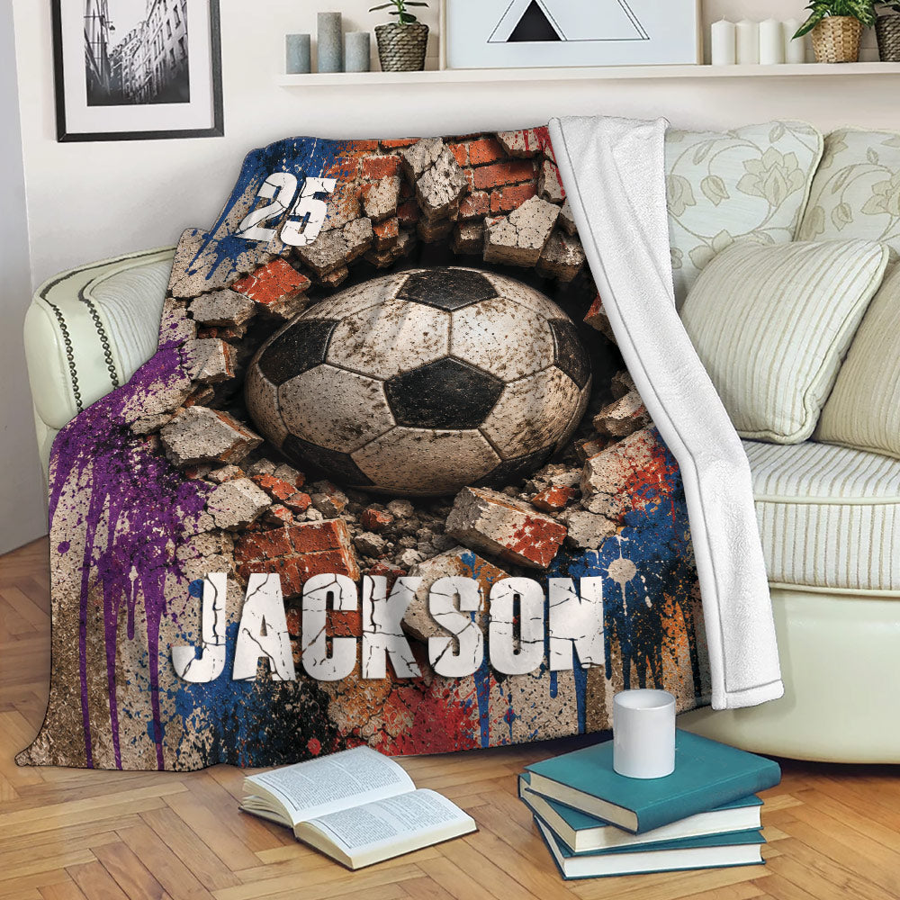 Soccer blanket draped over a sofa, featuring rugged ball artwork and a multicolor grunge background