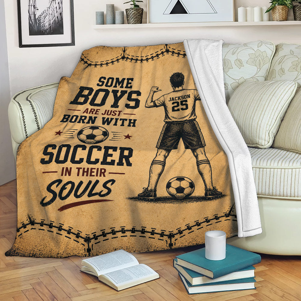 Soccer throw blanket draped over a couch with vintage player artwork and bold tan, black, and burgundy design