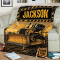 Construction truck throw blanket draped over a sofa with a detailed bulldozer scene and black and yellow work-zone design