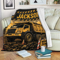 Construction truck throw blanket displayed on a couch with bold yellow and black dump truck artwork