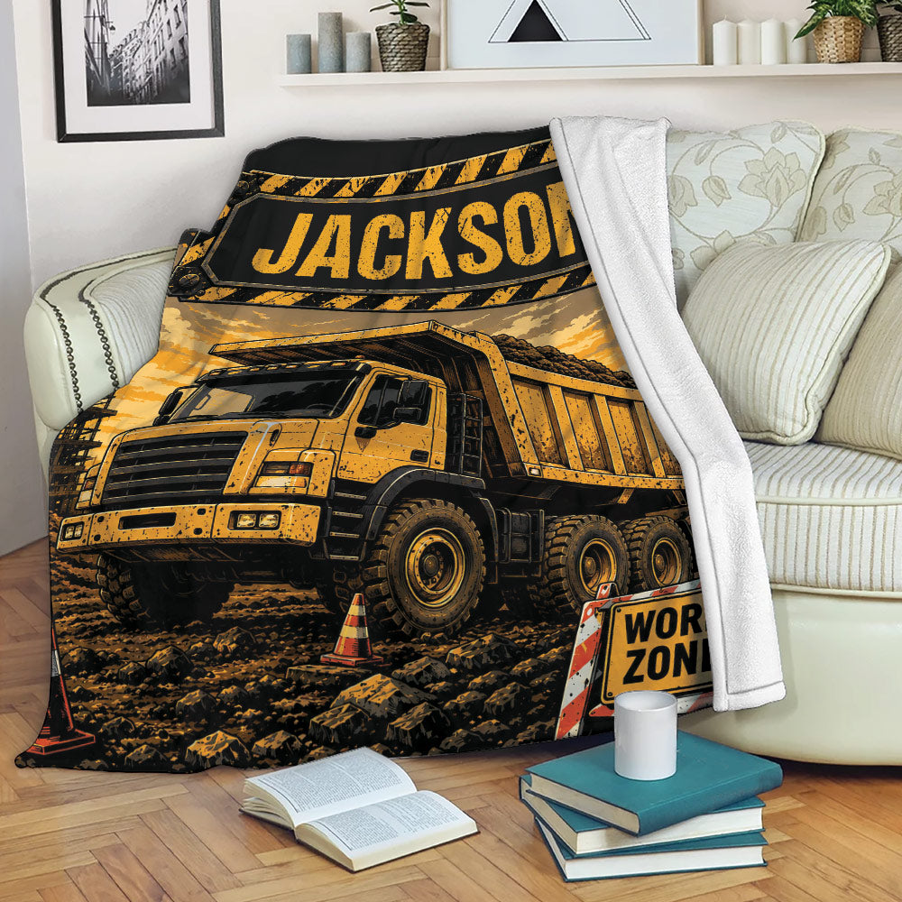Construction truck throw blanket displayed on a couch with bold yellow and black dump truck artwork