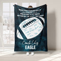 Teal football coach blanket displayed in a bright room with motivational sports artwork