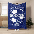 Blue soccer throw blanket held up indoors with large black and white soccer ball artwork