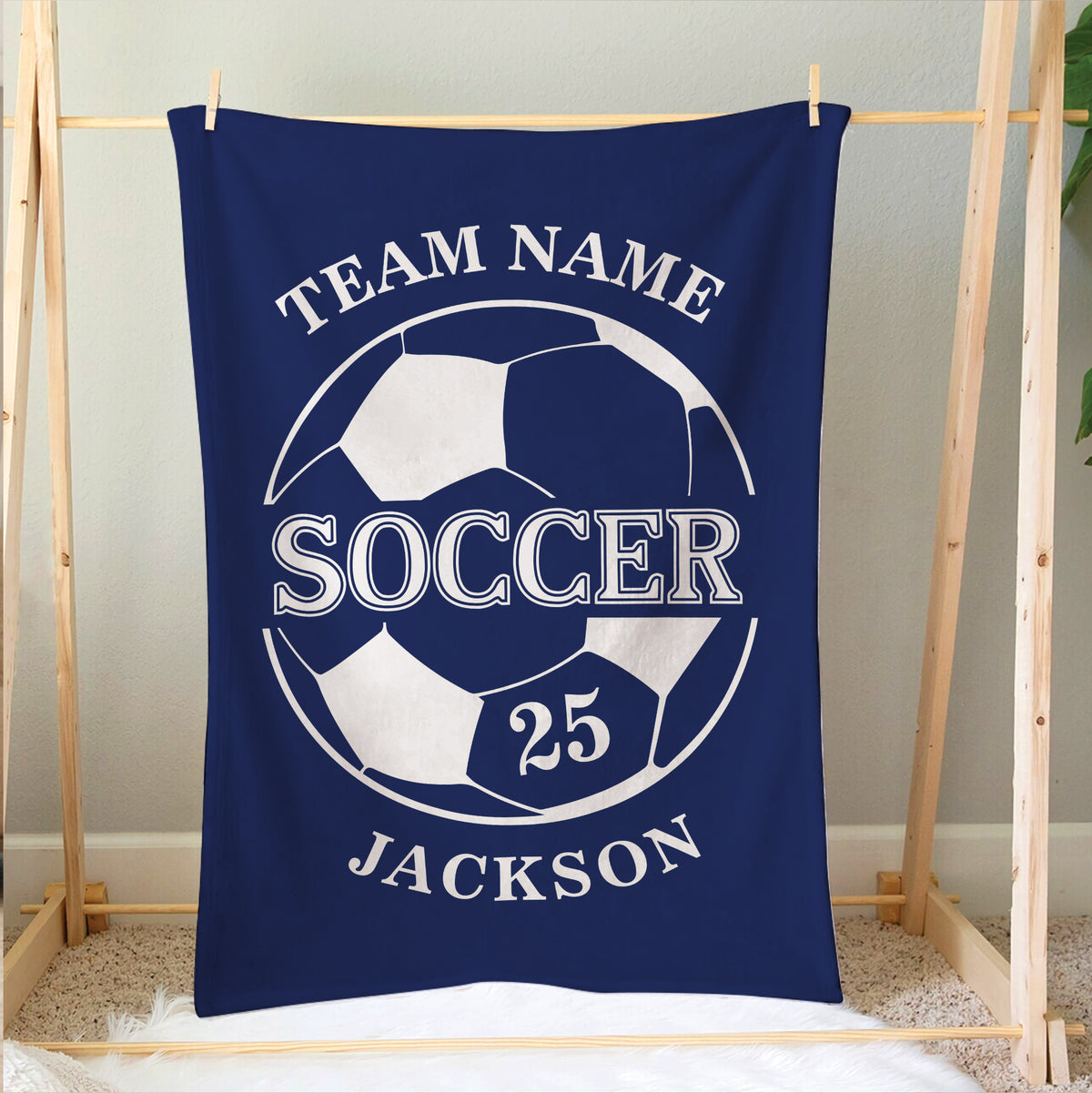 Blue soccer blanket hanging on a wooden frame with bold ball graphic and sports lettering