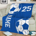 Blue soccer blanket draped over a sofa with large soccer ball graphics and bold sports design