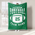 Green football throw blanket featuring bold white sports lettering and a large oval football design