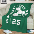 Green soccer throw blanket draped over a sofa, featuring bold white soccer artwork and team-inspired styling
