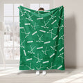 Green hockey throw blanket displayed with repeating hockey stick and puck artwork