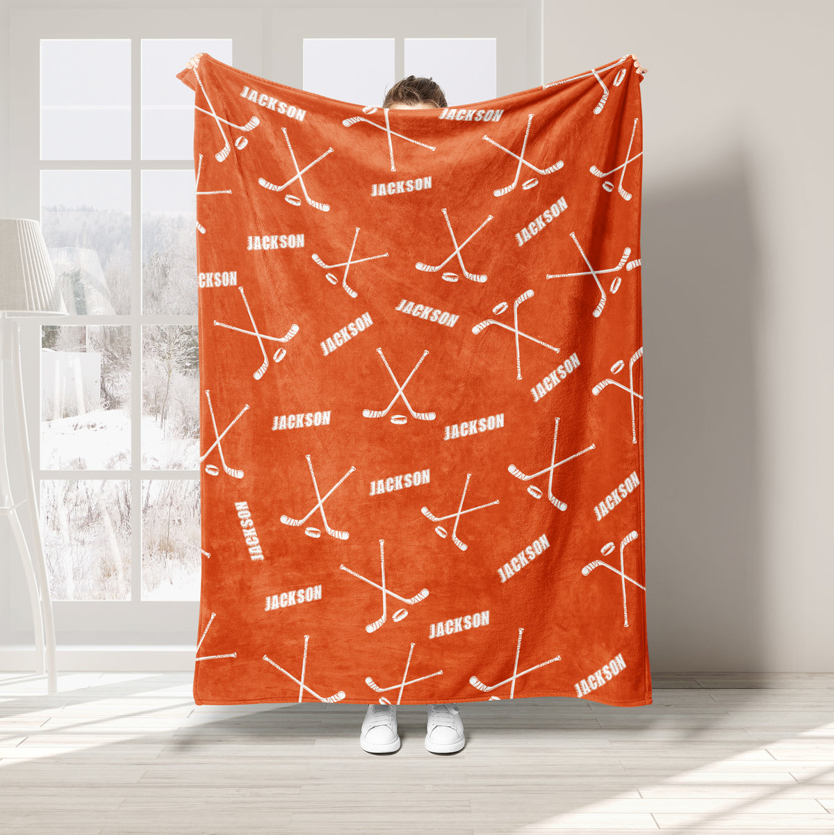 Orange hockey throw blanket displayed with white hockey sticks and puck pattern