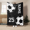 Black soccer throw blanket displayed in a room with white ball graphics and bold athletic-style artwork