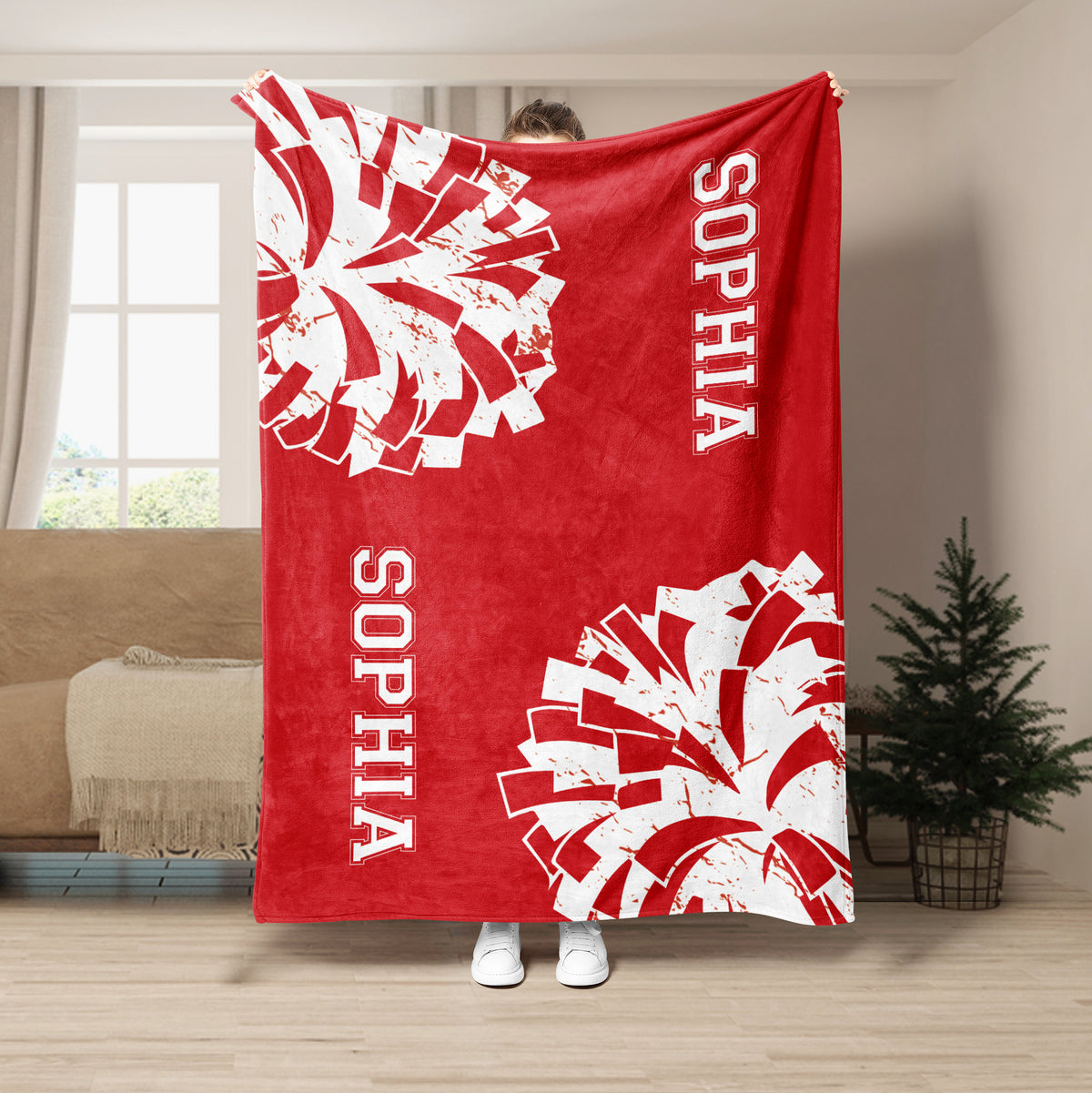Red cheerleading blanket held up indoors with contrasting white pom-pom artwork and cheer-themed lettering